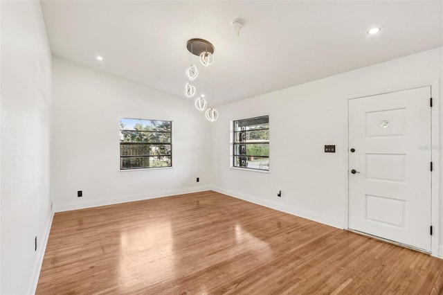 spare room with baseboards, lofted ceiling, and light wood-style floors