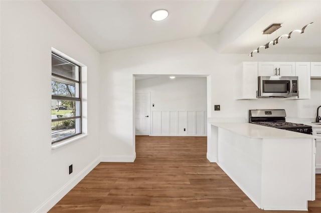 kitchen featuring wood finished floors, white cabinetry, appliances with stainless steel finishes, light countertops, and lofted ceiling