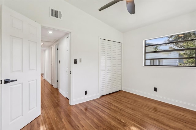 unfurnished bedroom with a closet, visible vents, baseboards, and wood finished floors