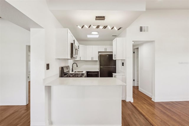 kitchen with visible vents, stainless steel microwave, freestanding refrigerator, light countertops, and gas range