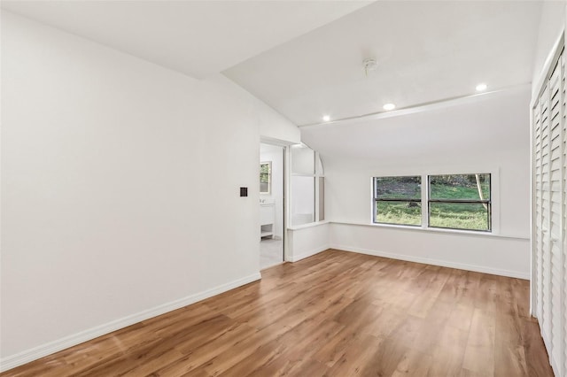 unfurnished room with vaulted ceiling, wood finished floors, and baseboards