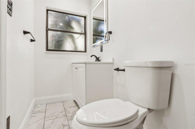 bathroom featuring baseboards, toilet, marble finish floor, and vanity