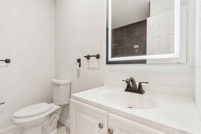 bathroom featuring baseboards, toilet, and vanity