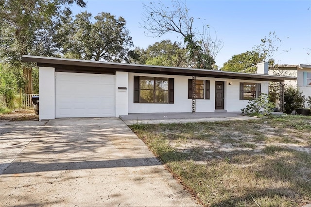 ranch-style home with a garage, concrete driveway, a chimney, and stucco siding