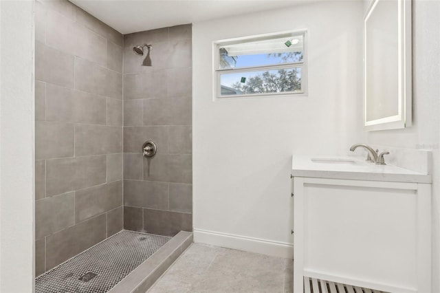 full bath with tile patterned flooring, baseboards, vanity, and a tile shower