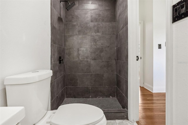 full bath featuring a stall shower, toilet, baseboards, and wood finished floors