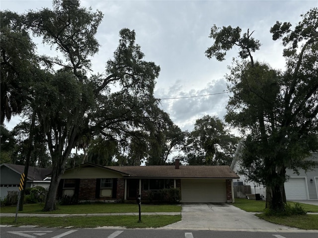 ranch-style house featuring driveway, a front lawn, fence, an attached garage, and brick siding