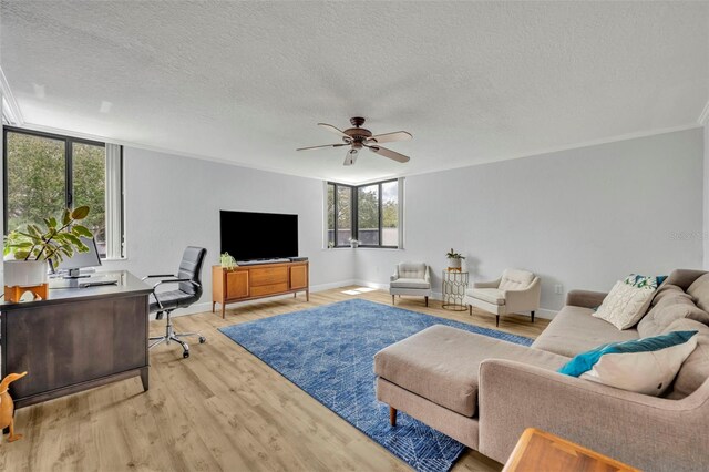 living room featuring crown molding, ceiling fan, light hardwood / wood-style floors, and a textured ceiling