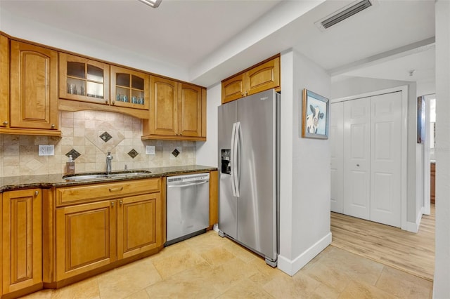 kitchen with backsplash, appliances with stainless steel finishes, sink, and dark stone counters