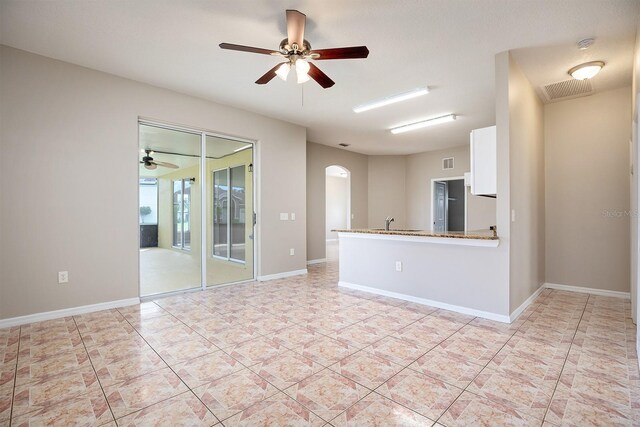 spare room with arched walkways, ceiling fan, light tile patterned floors, visible vents, and baseboards