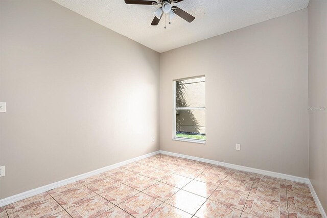 empty room with a ceiling fan, a textured ceiling, baseboards, and light tile patterned floors