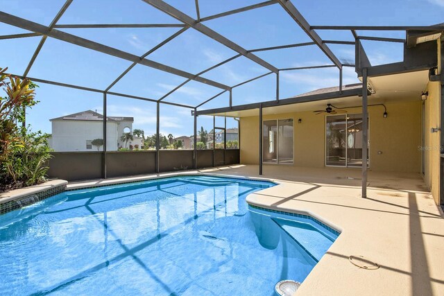 outdoor pool with a lanai, a patio area, and a ceiling fan