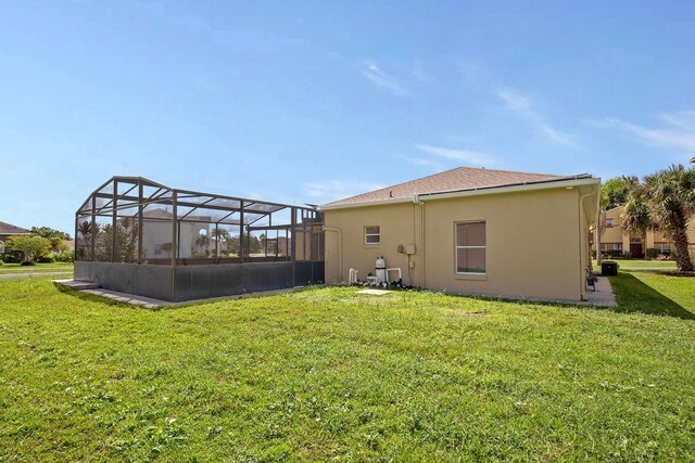 rear view of property with a lanai, a yard, and stucco siding