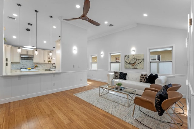 living room with high vaulted ceiling, ceiling fan, sink, and light wood-type flooring