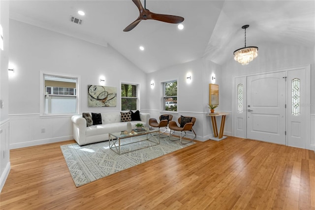 living room featuring light wood-type flooring, ceiling fan with notable chandelier, and high vaulted ceiling