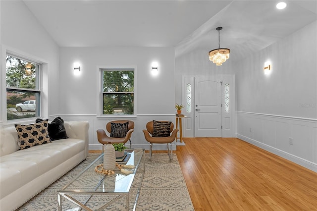 living room featuring lofted ceiling, a notable chandelier, and light hardwood / wood-style floors