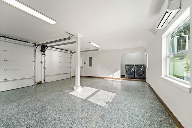 garage featuring electric panel, washer and clothes dryer, and a wall mounted air conditioner