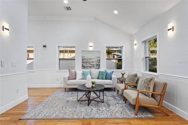 living room with crown molding, high vaulted ceiling, and light wood-type flooring