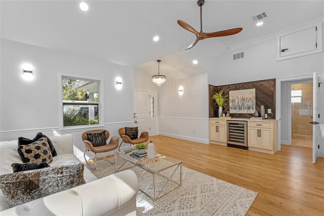 living room with ornamental molding, light hardwood / wood-style flooring, wine cooler, and ceiling fan