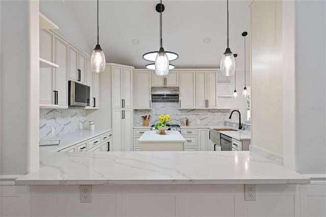 kitchen with hanging light fixtures, kitchen peninsula, and backsplash