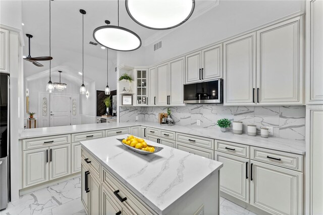 kitchen with hanging light fixtures, a center island, vaulted ceiling, light stone counters, and tasteful backsplash