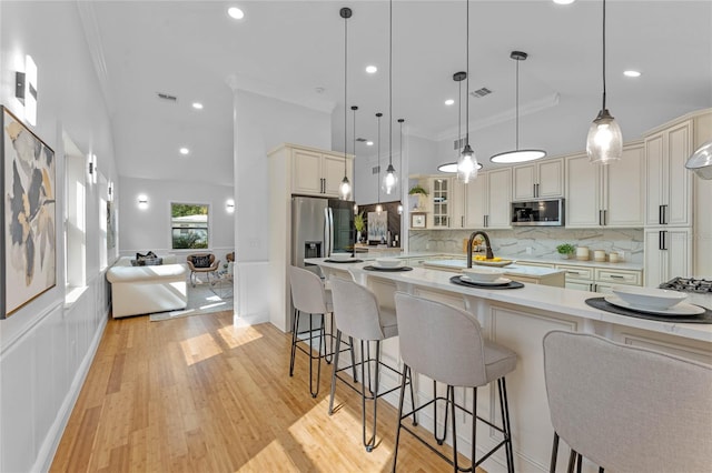 kitchen featuring light hardwood / wood-style flooring, decorative light fixtures, stainless steel appliances, a kitchen bar, and tasteful backsplash