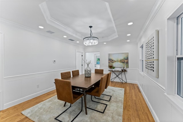 dining room featuring crown molding, light wood-type flooring, and a tray ceiling