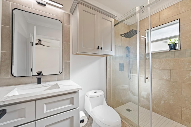 bathroom with vanity, a shower with shower door, toilet, ornamental molding, and ceiling fan