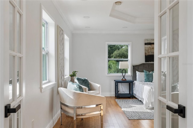 living area with ornamental molding, wood-type flooring, and a tray ceiling