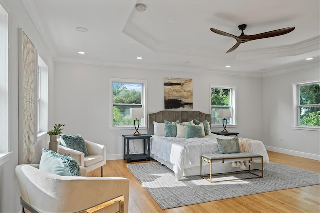 bedroom with crown molding, light hardwood / wood-style flooring, a tray ceiling, and ceiling fan