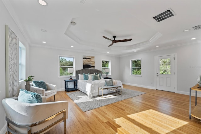 bedroom with ceiling fan, a raised ceiling, light hardwood / wood-style floors, and ornamental molding