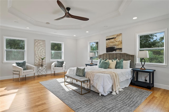 bedroom with ceiling fan, a raised ceiling, light hardwood / wood-style floors, and crown molding