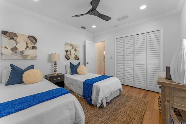 bedroom with crown molding, wood-type flooring, ceiling fan, and a closet