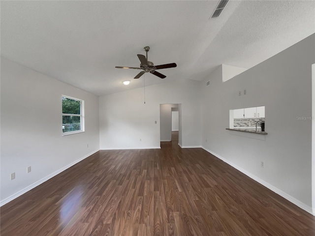 unfurnished living room with lofted ceiling, a ceiling fan, visible vents, baseboards, and dark wood finished floors