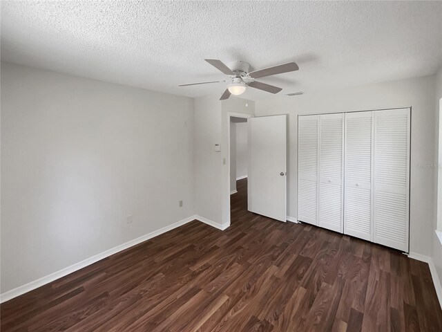 unfurnished bedroom featuring a closet, dark wood finished floors, baseboards, and ceiling fan