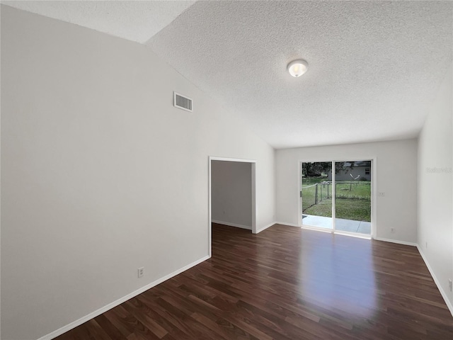 unfurnished room featuring a textured ceiling, visible vents, baseboards, vaulted ceiling, and dark wood-style floors