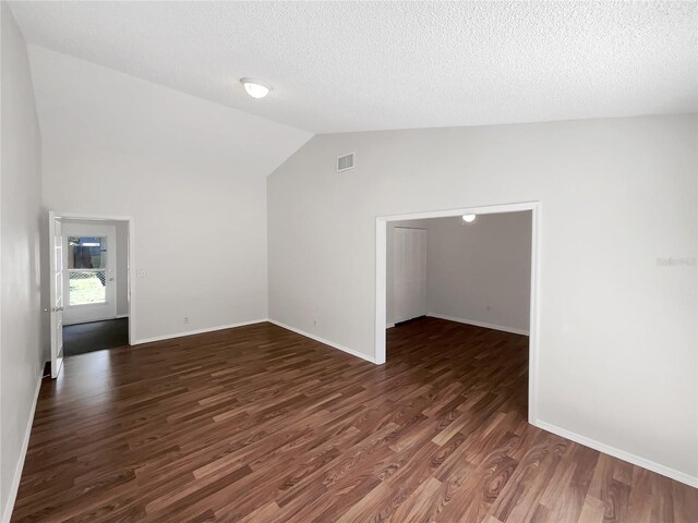 unfurnished room with vaulted ceiling, a textured ceiling, and dark hardwood / wood-style flooring