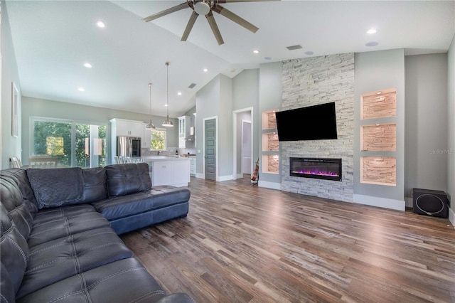 living room featuring high vaulted ceiling, ceiling fan, dark hardwood / wood-style floors, and a stone fireplace