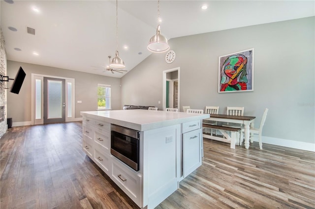 kitchen with white cabinets, pendant lighting, a kitchen island, and stainless steel microwave