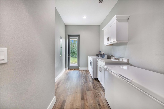 laundry room featuring cabinets, hardwood / wood-style floors, and washing machine and dryer