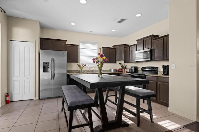 kitchen featuring dark brown cabinetry, sink, stainless steel appliances, and light tile patterned floors