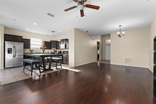 kitchen with a breakfast bar, a kitchen island, stainless steel appliances, light wood-type flooring, and dark brown cabinets