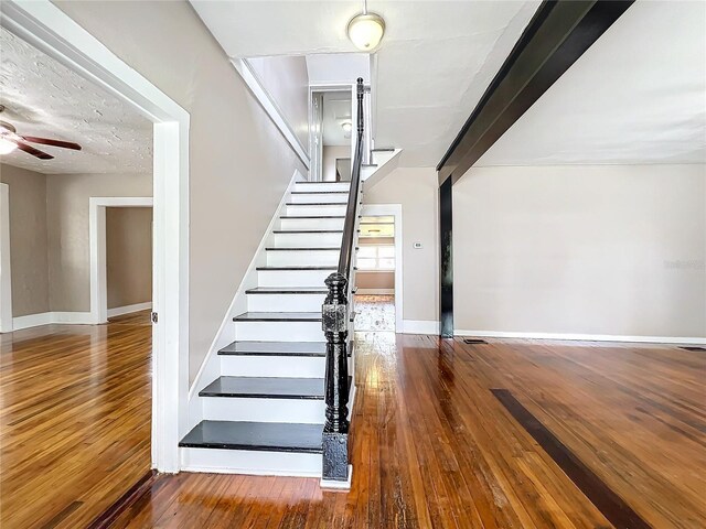 stairs featuring ceiling fan and hardwood / wood-style flooring