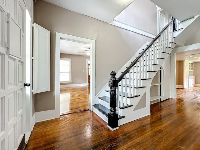 staircase with wood-type flooring and ceiling fan