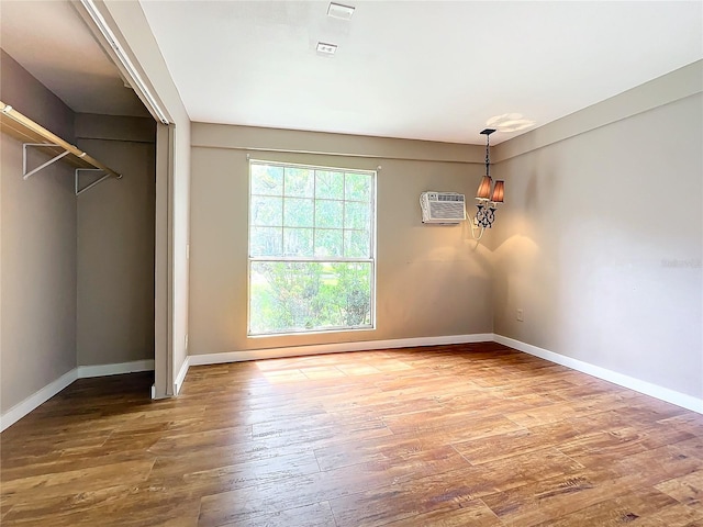 unfurnished bedroom featuring hardwood / wood-style flooring and a wall mounted air conditioner