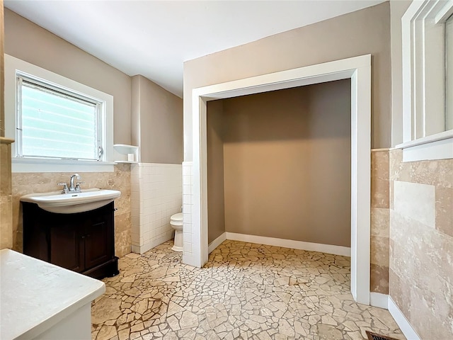 bathroom with vanity, toilet, and tile walls