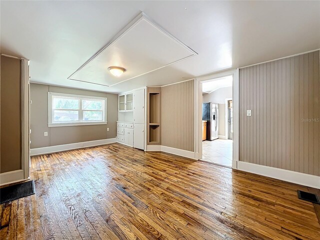 unfurnished room featuring wood walls and wood-type flooring