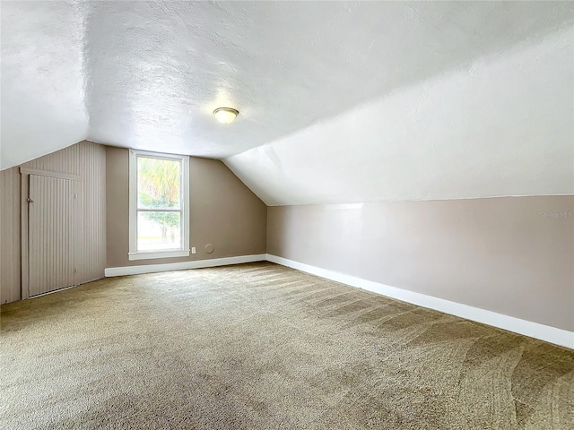 bonus room with a textured ceiling, lofted ceiling, and carpet floors