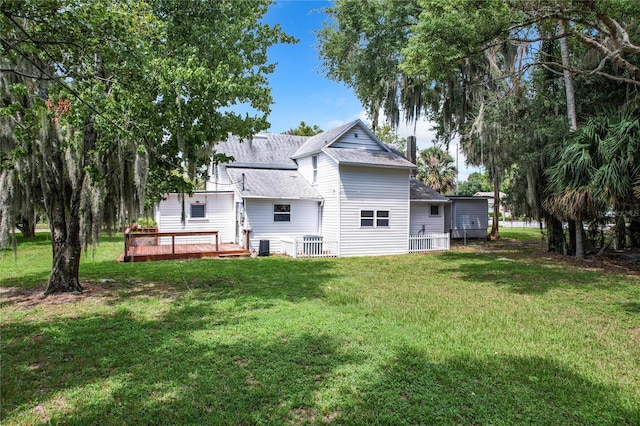 back of property featuring a wooden deck and a lawn