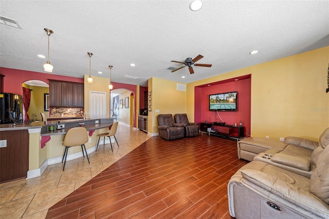 living room featuring a textured ceiling, ceiling fan, and hardwood / wood-style flooring